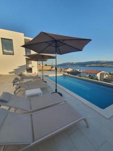 a group of lounge chairs and an umbrella next to a swimming pool at Holiday Villa Zubovici with private pool in Zubovići