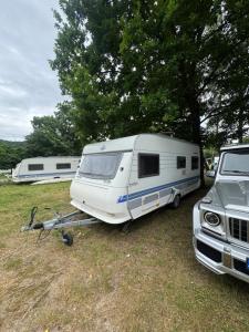 a white caravan parked in a field next to a truck at Karavan Ždáň in Slapy +5 photos
