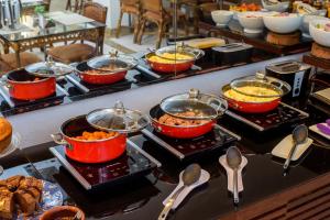 a buffet line with many pots and pans of food at Bahamas Duplex by WS in Campo Grande +9 photos