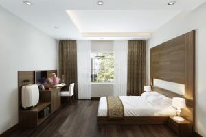a bedroom with a bed and a desk and a television at Eco Luxury Hotel Hanoi in Hanoi