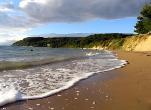 a beach with the ocean and a person in the water at Apartment Ljubac 2 in Ljubač