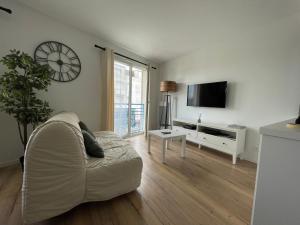 a living room with a couch and a clock on the wall at Le Coconing Moderne Centre Saint-Sébastien-sur-Loire, proche de Nantes in Saint-Sébastien-sur-Loire