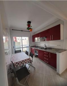 a kitchen with red cabinets and a table with chairs at Vacancia in Martil +12 photos