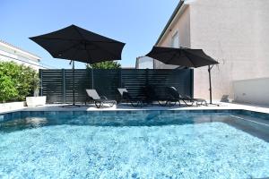 a swimming pool with two umbrellas and chairs and a swimming pool at Villa Matea pool house in Zadar