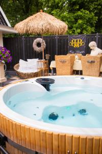 a jacuzzi tub with an umbrella in a backyard at B&B Huisje Schaufeli in Apeldoorn