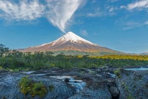 a mountain in the middle of a field with rocks at Hostal Livary Puerto Varas in Puerto Varas