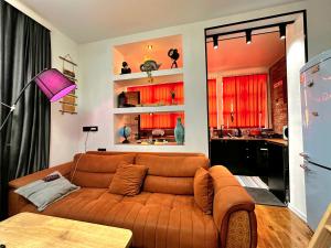 a living room with a brown couch and a kitchen at Maria's Dream House On Vera in Tbilisi City