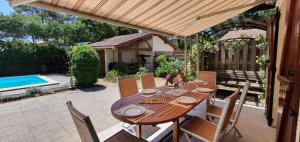 a wooden table and chairs on a patio with a pool at Résidence 03272-lacanau Ocean - Villa spacieuse , 3 chambres, 6 personnes, piscine privée à Lacanau océan MAE-0991 in Lacanau