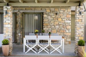 a white dining table on a patio with a stone wall at Gatzea Villas in Kato Gatzea
