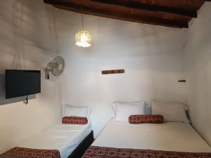 two beds in a room with a tv on the wall at MONCOGUA Casa de Hospedaje in Barichara