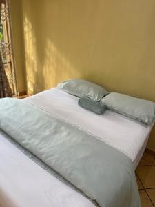 a large white bed with two pillows and amitt at Bugera's Palace in Pretoria