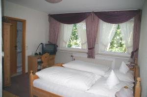 a bedroom with a bed with white sheets and windows at Hotel Restaurant Bieberstuben in Menden