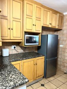 a kitchen with wooden cabinets and a black refrigerator at Bugera's Palace in Pretoria +45 photos