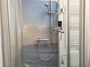 eine Dusche im Bad mit einem Gemälde des Ozeans in der Unterkunft Ferienhaus Ohrenqualle in Dornum