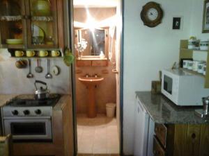 a kitchen with a stove and a sink and a microwave at Cabañas Ailen in Sierra de la Ventana