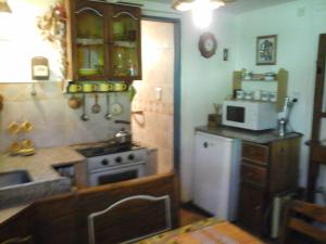 a kitchen with a stove and a microwave at Cabañas Ailen in Sierra de la Ventana