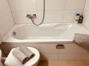 a bathroom with a toilet and a bath tub with two towels at Studio Wettingen möbliert, 25min bis Zürich in Wettingen +18 photos