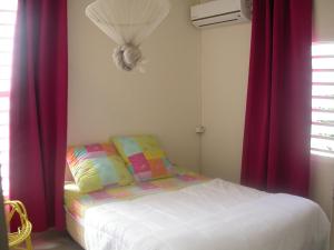- une chambre avec un lit et des rideaux rouges dans l'établissement Maison de Vacances à St Anne Martinique, à Sainte-Anne