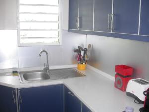 une cuisine avec des armoires bleues et un évier dans l'établissement Maison de Vacances à St Anne Martinique, à Sainte-Anne 15 autres photos
