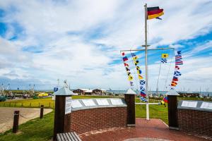 a flag pole with flags on top of a brick wall at Kleine Austernperle in Dornumersiel +6 photos
