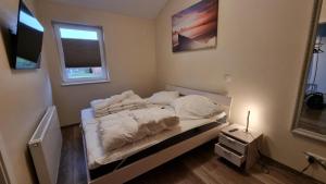 a bedroom with a bed with white sheets and a window at Ferienhaus Strandengel in Dorum Neufeld