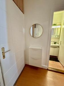 a white bathroom with a mirror and a door at Studio moderne et chaleureux au coeur de Geneve - parfait pour courts sejours in Geneva