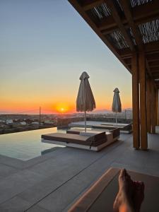 a person laying on the edge of a swimming pool with the sunset at Mystic Heaven in Mýkonos City