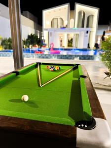 a green pool table with a cue ball on it at Amora Villa in Al Rama