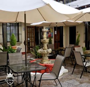 a patio with tables and umbrellas and a fountain at Real Marquez Hotel in Antigua Guatemala +19 photos