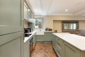 a kitchen with green cabinets and a white counter top at The Library Suite in Marske +8 photos