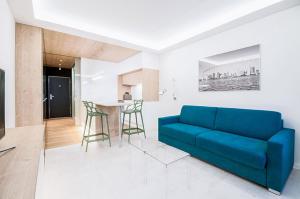 a living room with a blue couch and a kitchen at White apartment in Playa del Carmen