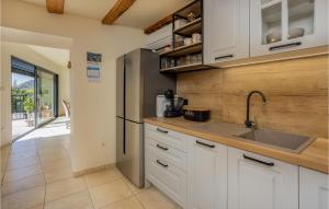 a kitchen with white cabinets and a stainless steel refrigerator at Cozy Home In Grizane-Belgrad in Grižane