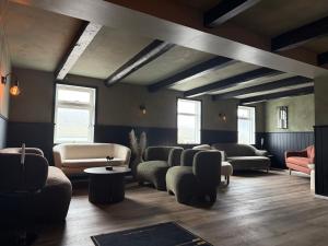 a living room with couches and chairs and windows at Hótel Gerpir in Neskaupstaður