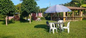 a table and chairs and an umbrella in the grass at Finca las Margaritas in Estación El Salto