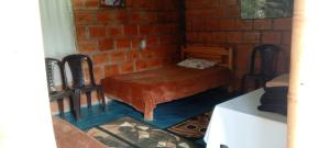 a room with a bed and two chairs and a brick wall at Finca las Margaritas in Estación El Salto