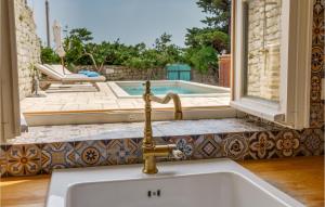 a kitchen sink with a faucet in front of a pool at Pet Friendly Home In Osor in Osor