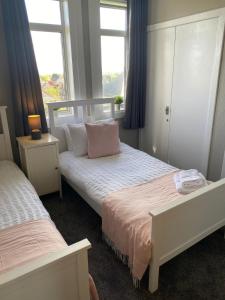 a bedroom with two beds and two windows at Glen Mhor - Beautiful two bedroom apartment Dunfermline in Townhill