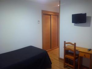 a bedroom with a bed and a desk and a television at Hostal Plaza Mayor de Almazán in Almazán