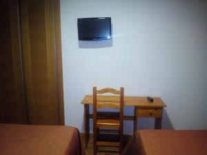 Habitación con mesa y TV en la pared. en Hostal Plaza Mayor de Almazán, en Almazán