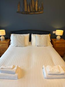 a large white bed with two towels on it at Bryn Melyn Apartments in Barmouth