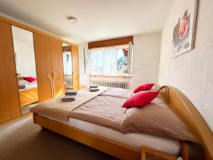 una camera da letto con un letto grande con cuscini rossi di Bright apartment close to center a Grächen
