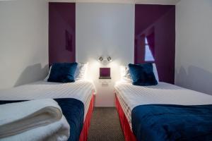 a hotel room with two beds with blue pillows at OYO The Bentleys Hotel in Newcastle upon Tyne