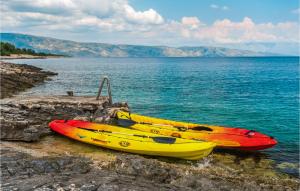 three kayaks sitting on the rocks near the water at Villa Aqua in Vrbanj