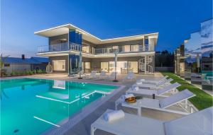 une grande maison avec une piscine et des chaises blanches dans l'établissement Villa Gabrijela Kastelir, à Kaštelir