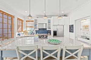 a kitchen with a large island with chairs around it at Quaint 2BR/25BA Cottage Nestled Between 30A & Panama City Beach! Sleeps 6! in Carillon Beach