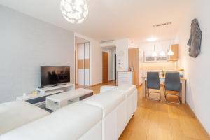 Una sala de estar con un sofá blanco y un televisor. en Downtown apartment in the heart of the new city center, 4 persons, parking, en Bratislava