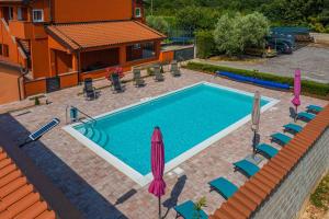 einen Pool mit Stühlen und Sonnenschirmen neben einem Haus in der Unterkunft Apartment Pula 6 in Pula