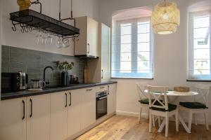 a kitchen with white cabinets and a table and chairs at Casa Hermann 1917 - Citadel Apartments in Făgăraş