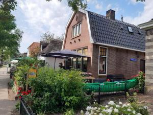 a house with a green fence and some flowers at Apartment in Giethoorn by Scenic Canals in Giethoorn