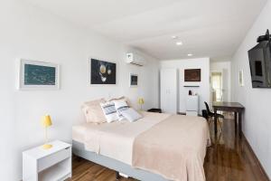 a white bedroom with a bed and a desk at Cobertura com linda vista da praia do Pêpe in Búzios
